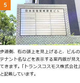 5　歩道側、右の頭上を見上げると、ビルのテナント名などを表示する案内版が見えてきます。「トランスコスモス株式会社」と記載しています。