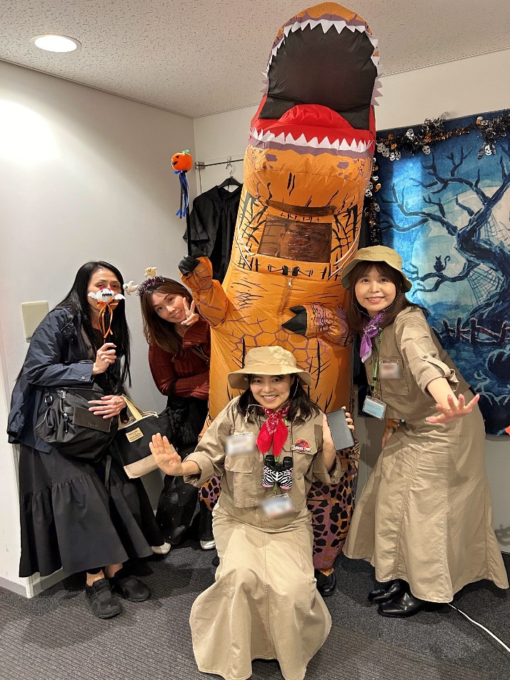 ティラノサウルスのコスプレをした男性のまわりに4人の女性がポーズをとっている